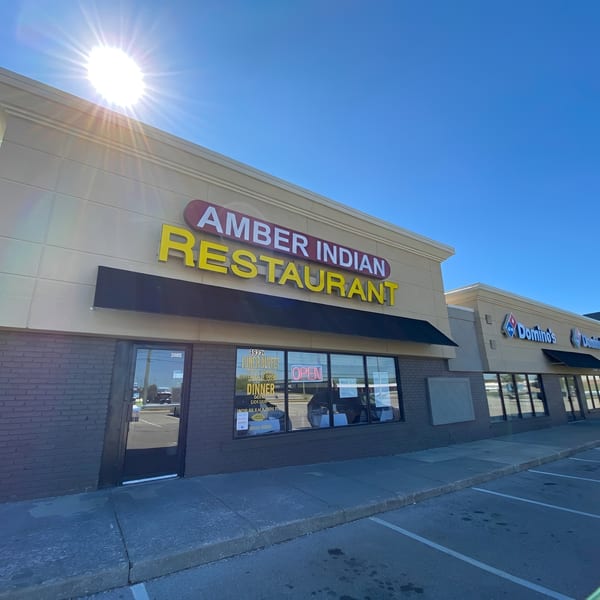 The exterior of Amber Indian Restaurant and Domino's Pizza on a sunny day.